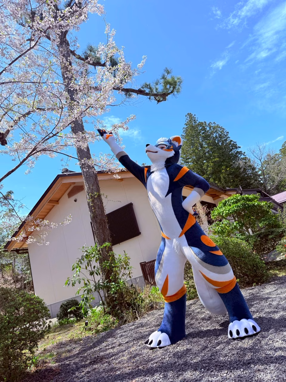 Blue NEOERA character beside spring blossoms